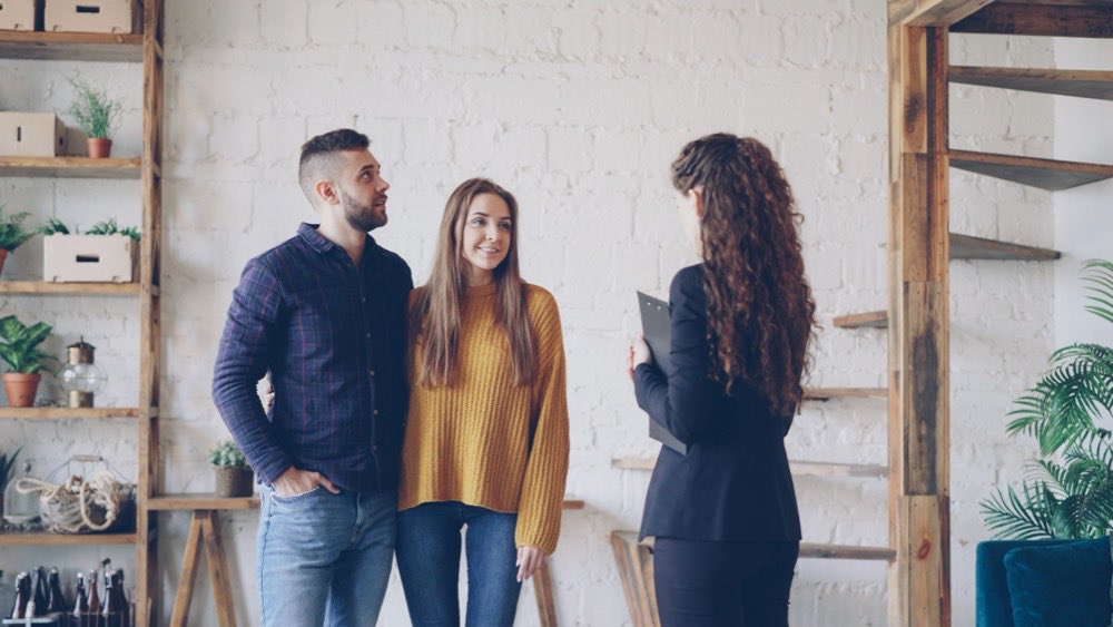 Letting agent with a clipboard showing an apartment to a young couple