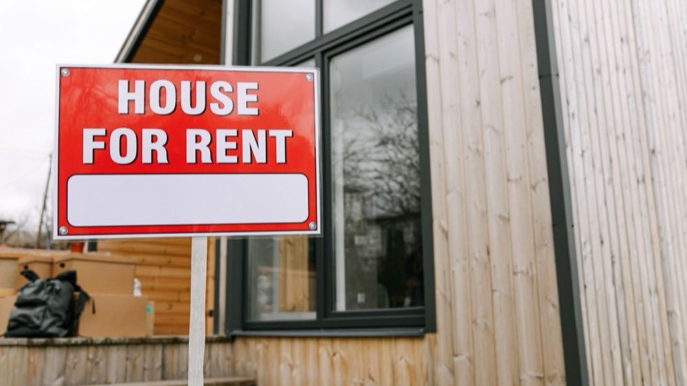 Red house-for-rent sign fixed to the window of a modern building