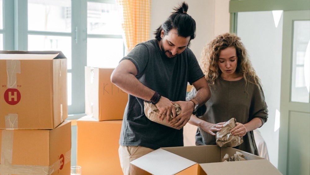 Couple unpacking a cardboard box together in a bright room