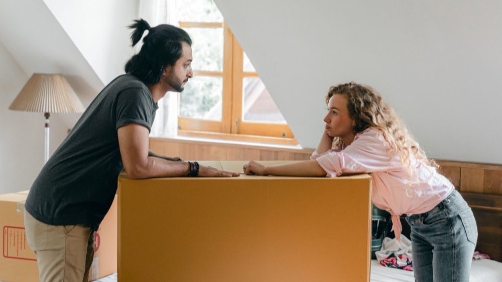Man and a young girl packing a cardboard box together in an attic room