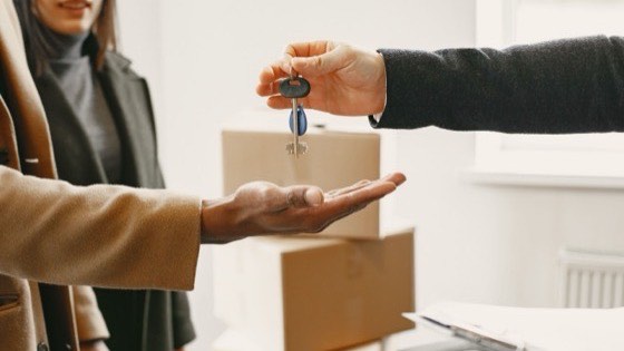 Hand dropping a key into an open palm above a cardboard box